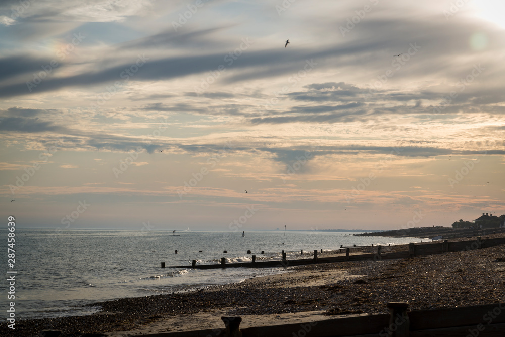 Seashore with groynes preventing beach erosion at Ferring at sunset, West Sussex, England, UK