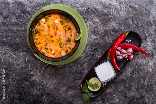 famous delicious Thai Tom yum spicy soup with shrimps and coconut milk on black table. flat lay