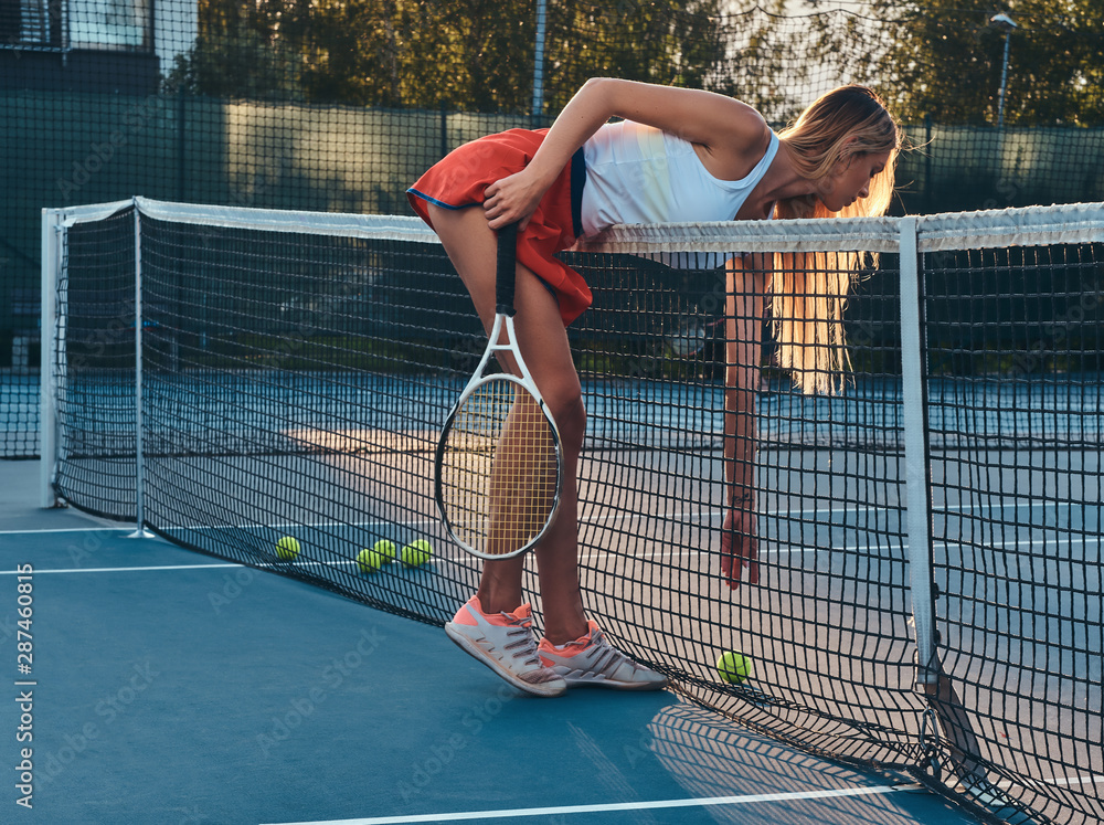Young sportive woman is leaning to take a tennis ball over net at tennis  court. Stock Photo | Adobe Stock