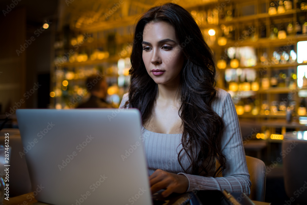 Gorgeous woman entrepreneur reading information on web site via laptop computer while sitting in restaurant Gorgeous woman entrepreneur reading information on web site via laptop computer while sitting in restaurant