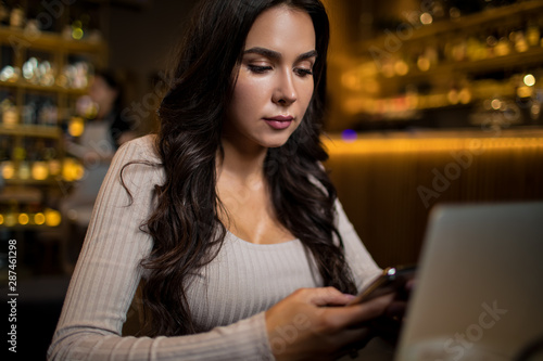 Successful woman entrepreneur received notifications on mobile phone while relaxing in coffee shop 
