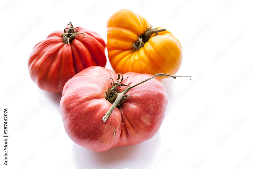 Three tomatoes of different colors and shapes on a white background. Isolated composition. Copy space - obrazy, fototapety, plakaty 