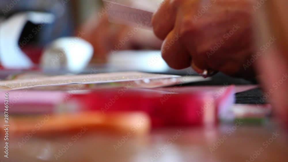 A close shot of hands gluing on paper on scrapbook A close shot of hands gluing on paper on scrapbook