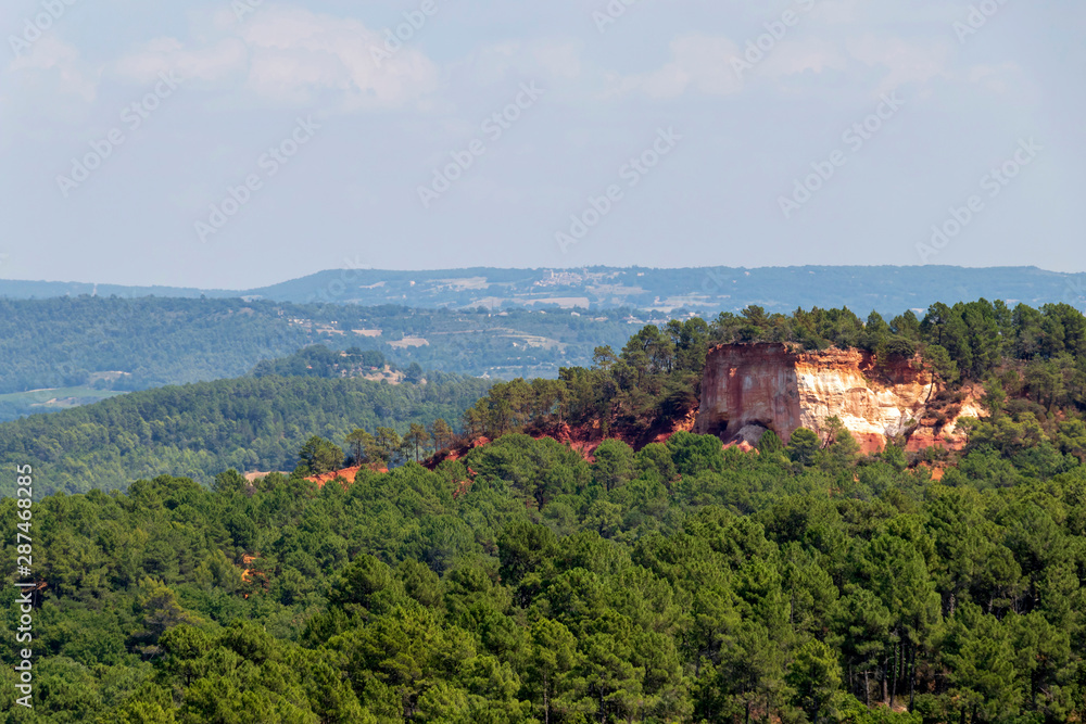 Ochre Trail in Roussillon, Hiking path in orange ocher cliffs surrounded by green forest in Provence, Southern France Ochre Trail in Roussillon, Hiking path in orange ocher cliffs surrounded by green forest in Provence, Southern France