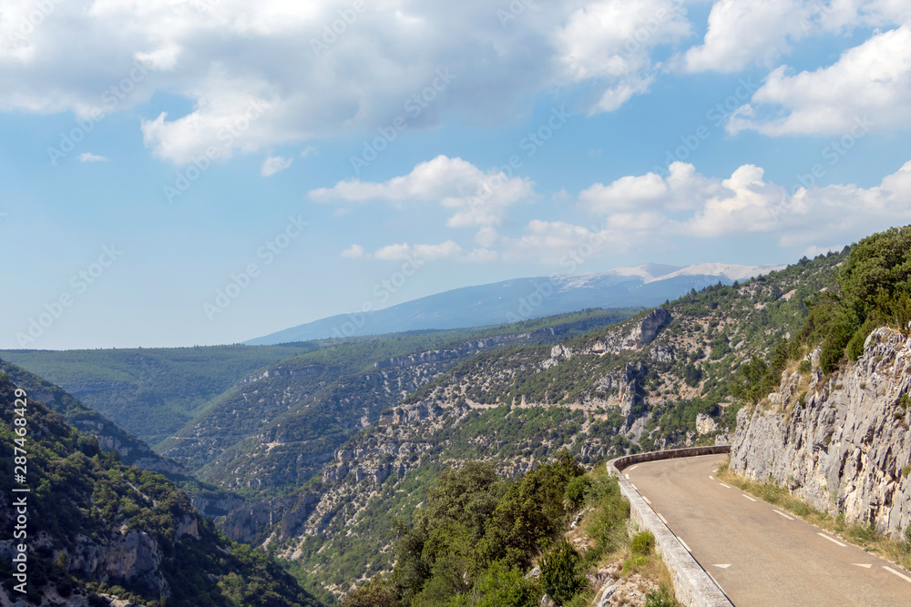 Empty road in the Canyon Gorges de la Nesque, gray cliffs with green forest in summer sunny day in Provence, South France