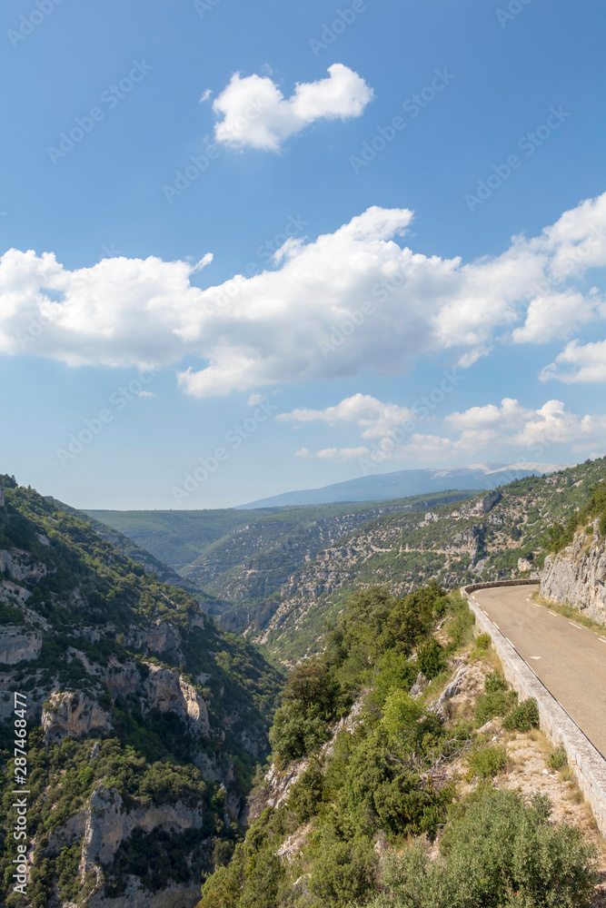 Empty road in the Canyon Gorges de la Nesque, gray cliffs with green forest in summer sunny day in Provence, South France Empty road in the Canyon Gorges de la Nesque, gray cliffs with green forest in summer sunny day in Provence, South France
