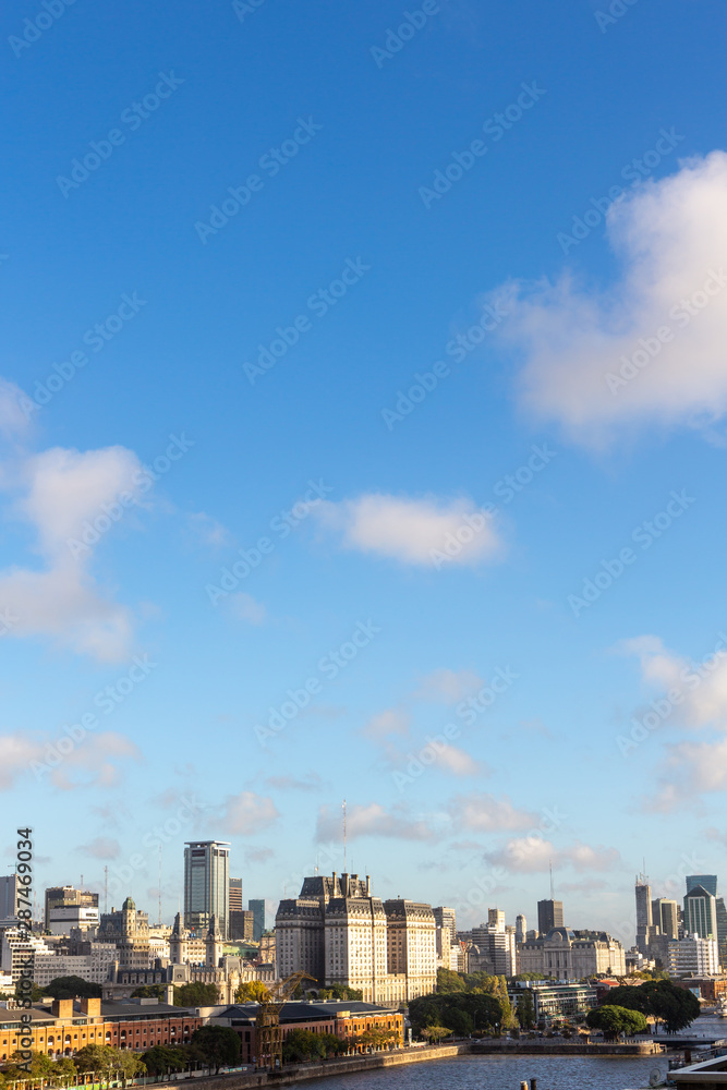 Beautiful skyline view of Buenos Aires, Argentina city center from Puerto Madero in sunny summer day with blue sky. Skyscraper office architecture, old buildings and city apartments.