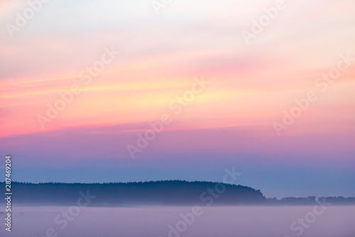Morning before sunrise. A multicolored sky and a sea of mist beneath it.