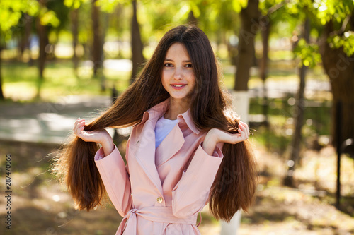 Portrait of a young brunette girl in pink coat on a background of autumn park photo