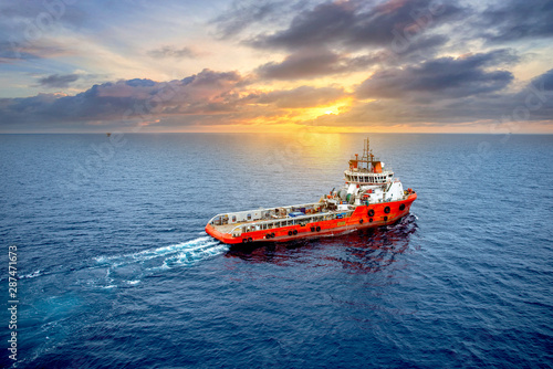 Supply vessel transport cargo for rig platform offshore at sunset.