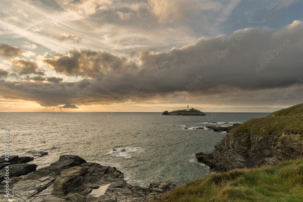 Godrevy Lighthouse at sunset with beautiful cloudy sky and warm glow, Cornwall, UK