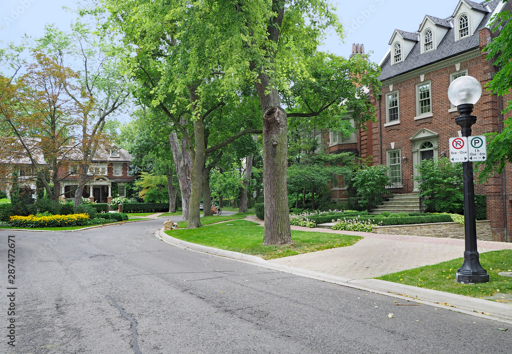 Tree-lined residential street with large brick detached houses
