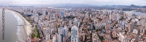 Beautiful aerial drone view of Santos city in Sao Paulo, Brazil. Panoramic Santos skyline with beach, sea, streets and buildings with mountains in the background in foggy day. © Imago Photo