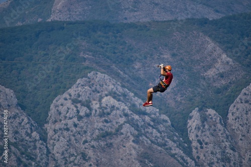 Male man is doing extreme zip-lining in the mountains in Montenegr.Close-up image of extreme sports.