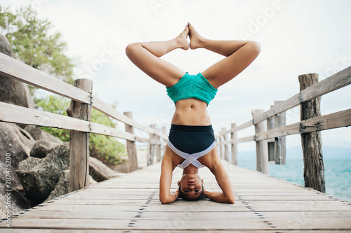 Young woman doing yoga on the wooden bridge photo