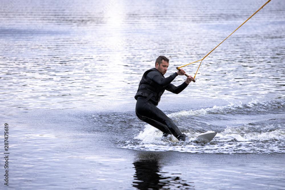 Beginner wakeborder learning surf. Spectacular kind of Extreme sport. Young handsome man surfing on water. Summer view of water sport extreme and wakeboarder training. Man in wetsuit bathing in lake. Beginner wakeborder learning surf. Spectacular kind of Extreme sport. Young handsome man surfing on water. Summer view of water sport extreme and wakeboarder training. Man in wetsuit bathing in lake.
