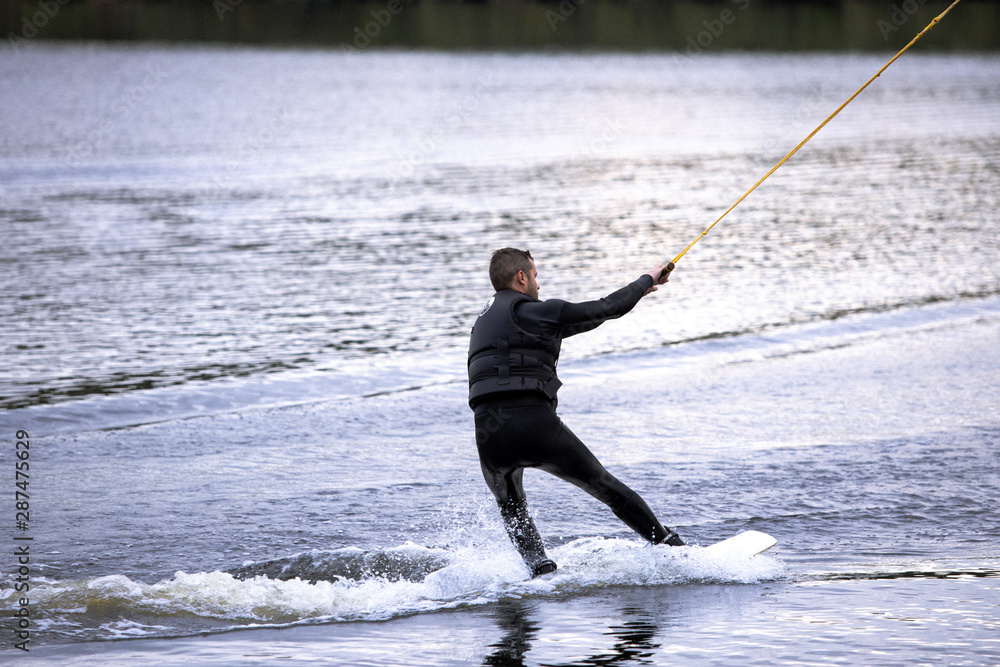 Beginner wakeborder learning surf. Spectacular kind of Extreme sport. Young handsome man surfing on water. Summer view of water sport extreme and wakeboarder training. Man in wetsuit bathing in lake. Beginner wakeborder learning surf. Spectacular kind of Extreme sport. Young handsome man surfing on water. Summer view of water sport extreme and wakeboarder training. Man in wetsuit bathing in lake.