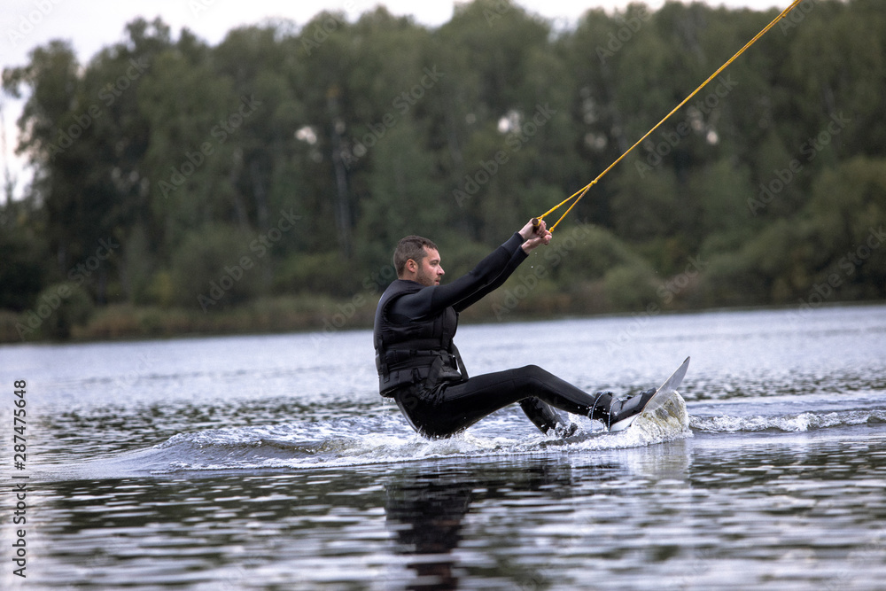 Beginner wakeborder learning surf. Spectacular kind of Extreme sport. Young handsome man surfing on water. Summer view of water sport extreme and wakeboarder training. Man in wetsuit bathing in lake. Beginner wakeborder learning surf. Spectacular kind of Extreme sport. Young handsome man surfing on water. Summer view of water sport extreme and wakeboarder training. Man in wetsuit bathing in lake.