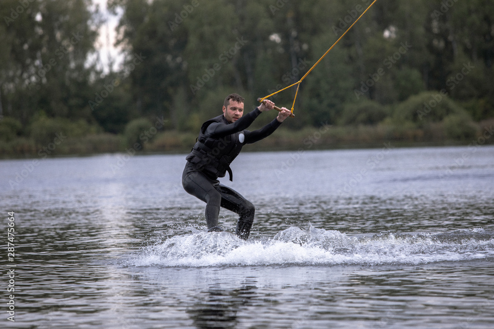 Beginner wakeborder learning surf. Spectacular kind of Extreme sport. Young handsome man surfing on water. Summer view of water sport extreme and wakeboarder training. Man in wetsuit bathing in lake. Beginner wakeborder learning surf. Spectacular kind of Extreme sport. Young handsome man surfing on water. Summer view of water sport extreme and wakeboarder training. Man in wetsuit bathing in lake.