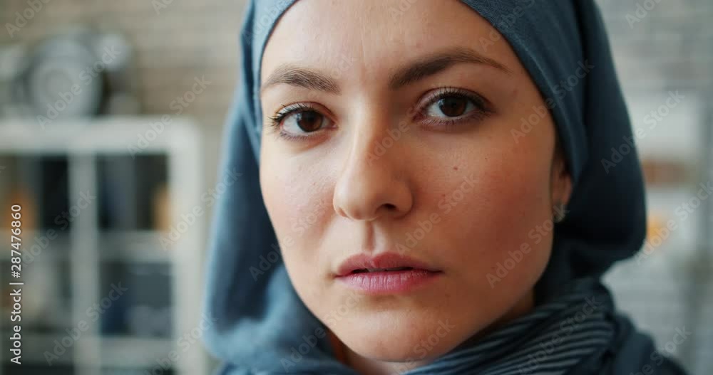 Close-up of attractive Middle Easter lady in hijab looking at camera standing in office on brick wall background. People, lifestyle and youth concept. Close-up of attractive Middle Easter lady in hijab looking at camera standing in office on brick wall background. People, lifestyle and youth concept.
