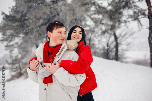 Young couple in a winter park. Man with a red sharf. Lady in a red jacket photo