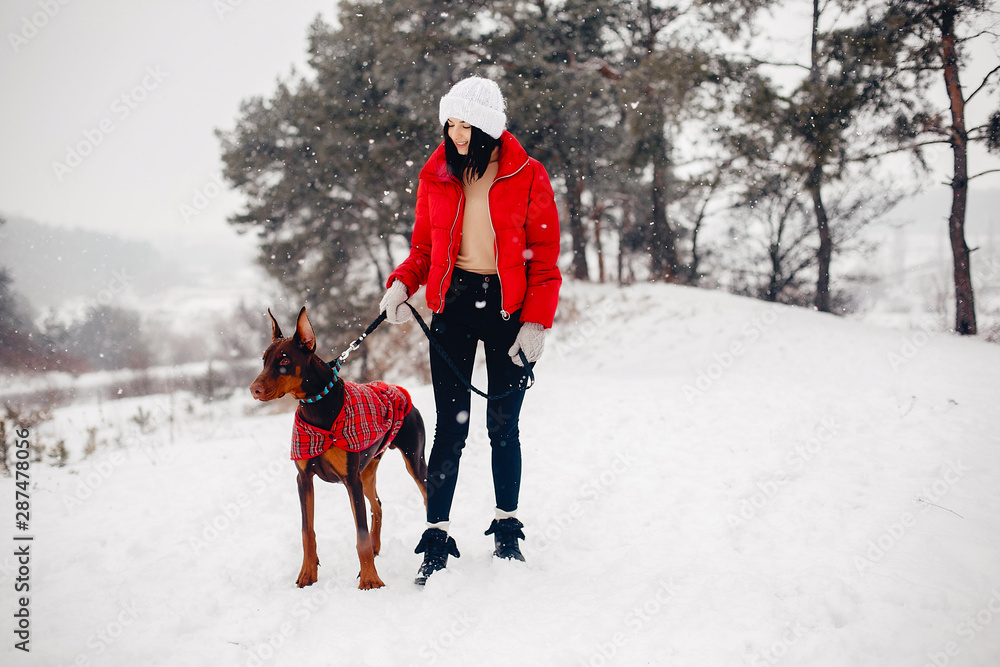 Cute girl walking in a winter park. Woman in a red jacket. Lady with a dog