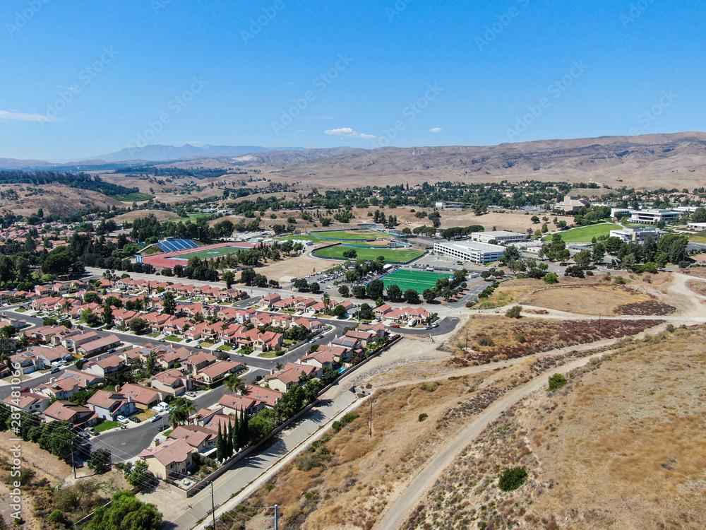 Fototapeta premium Aerial view of small neighborhood with dry desert mountain on the background in Moorpark