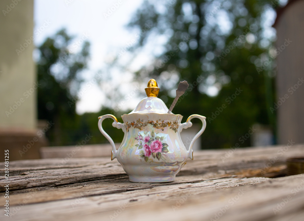 porcelain sugar bowl with a spoon on a table in the garden porcelain sugar bowl with a spoon on a table in the garden