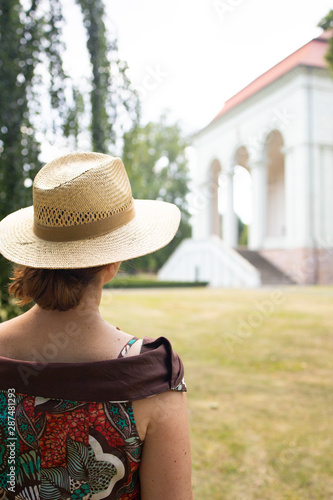  Elegant woman in a hat walking towards the historic palace, Czech Republic