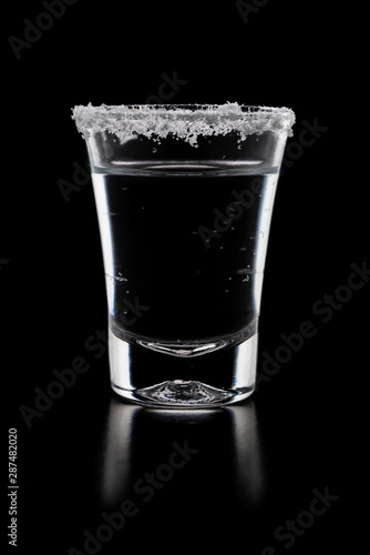 Tequila in a glass with salt isolated black background