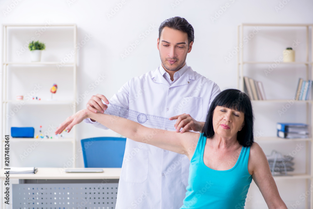 Obraz premium Young male doctor examining old female patient