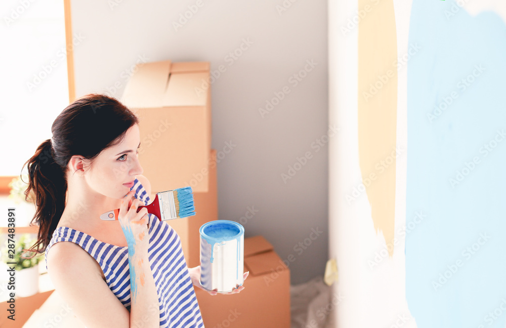 Happy smiling woman painting interior wall of new house. Happy smiling woman Happy smiling woman painting interior wall of new house. Happy smiling woman