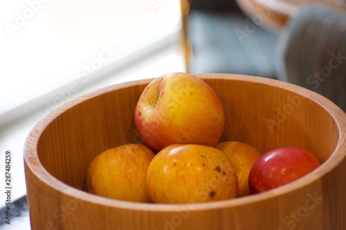 Red and yellow apples sitting in a wooden bowl