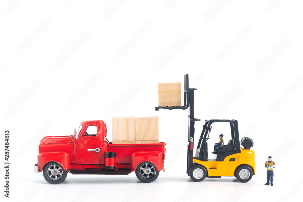 Miniature workers model controlling forklift loading cargo on pickup isolated on white background in transportation concept