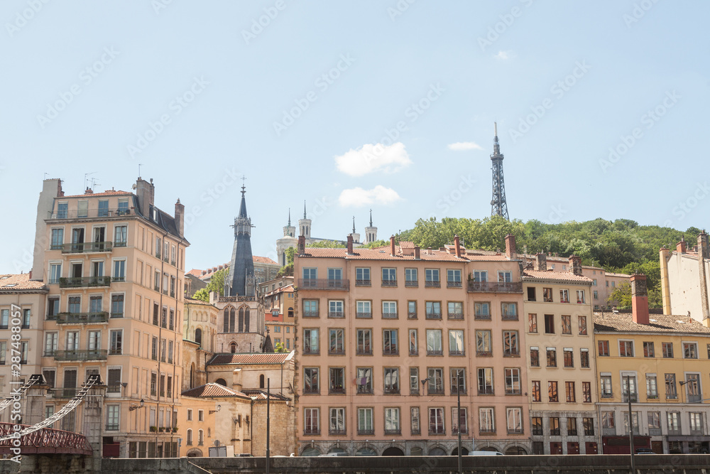 Facade of the old buildings of the vieux Lyon (Old Lyon) in France facing Colline de Fourviere Hill on the riverbank of the Rhone river during a summer afternoon