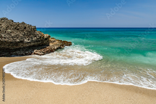Ocean foamy waves at the beach near rocks, crystal clear turquoise water, Sosua, Puerto Plata, Dominican Republic © oleksandra