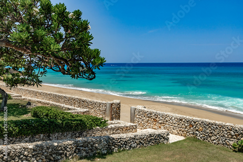 Summer caribbean coastline panoramic view, tropical green garden with stairs to the beach with stone wall, splashes, white Aleli tree, Sosua, Puerto Plata. Dominican Republic © oleksandra