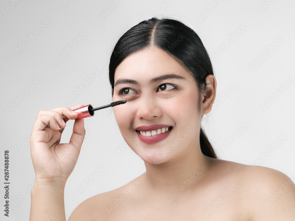 Close-up portrait of nice lovely cute sweet attractive cheerful positive Asian woman holding in hands applying trendy black mascara isolated over gray background. Close-up portrait of nice lovely cute sweet attractive cheerful positive Asian woman holding in hands applying trendy black mascara isolated over gray background.