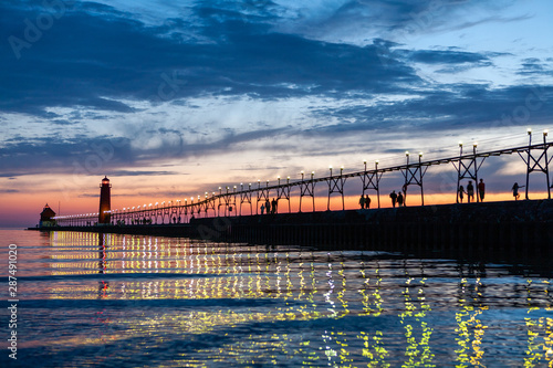 Grand Haven Lighthouse at sunset with catwalk lights reflected in Lake Michigan photo
