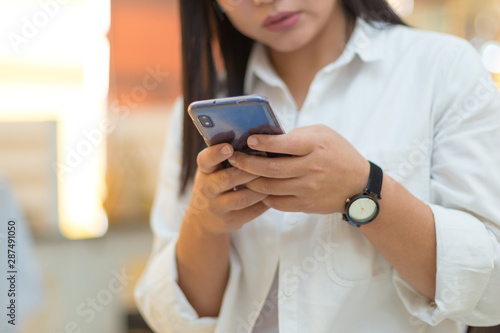 Female hand holds a smartphone. She uses a smartphone and sits in the office. Sexy girl