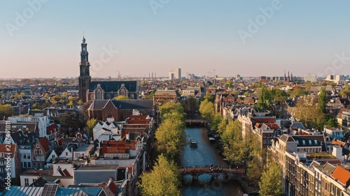 Amsterdam, Netherlands: drone view of Westerkerk church and narrow canal with bridges and boats traffic photo