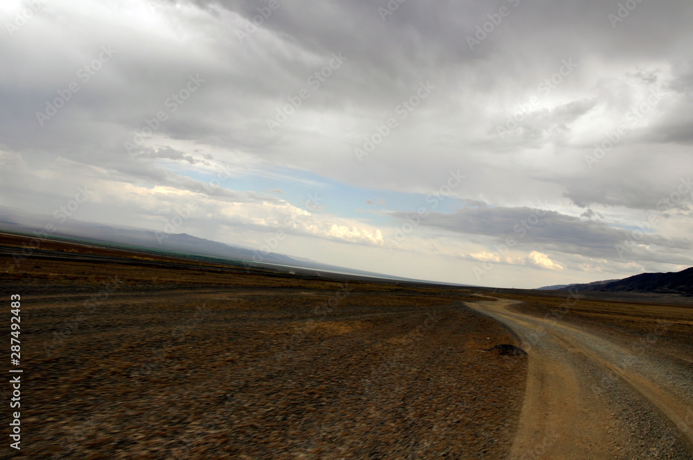 Naklejka premium Grass Field and mountains at dramatic overcast sky in Kazakhstan, central Asia
