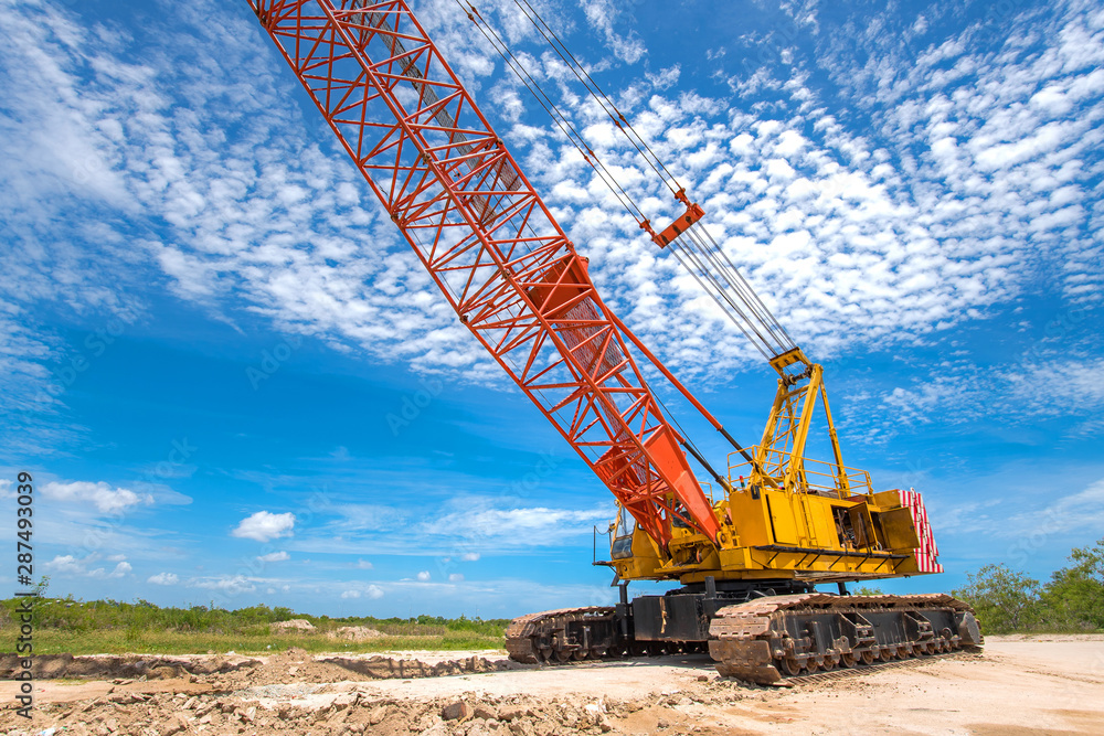 Yellow mobile crane on operation in construction site with cloudy sky background Yellow mobile crane on operation in construction site with cloudy sky background