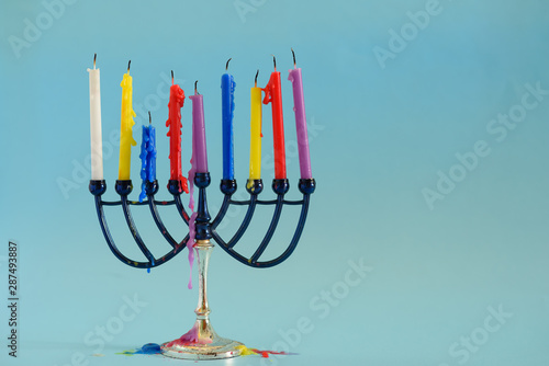 Image of Jewish holiday Hanukkah background with menora traditional candelabra and colorful candles .Copy space for text.