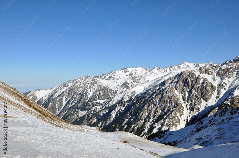 high snowy mountains in cloudy day, mounting skiing resort Shymbulak or Chimbulak, Almaty, Kazakhstan