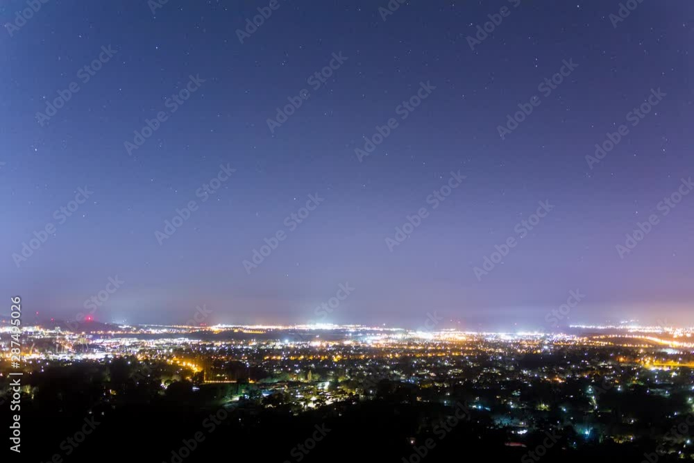 City night lights and under a timelapse of moving stars City night lights and under a timelapse of moving stars
