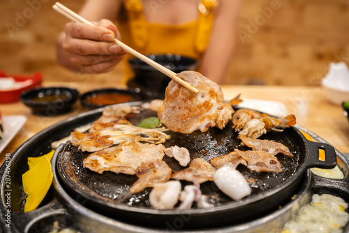 hands using chopsticks to grilled pork barbecue