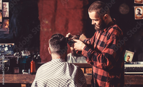 Man visiting hairstylist in barbershop. Bearded man in barbershop. Work in the barber shop. Man hairstylist. Hairdresser cutting hair of male client. Hairstylist serving client at barber shop