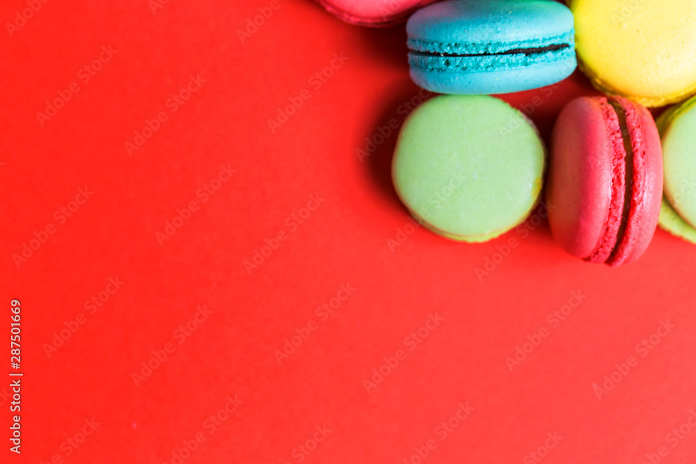 Closeup of red background for copy space with colorful macaroons in the corner. Closeup of red background for copy space with colorful macaroons in the corner.