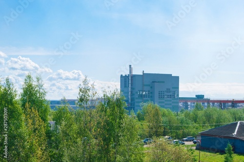 Summer industrial landscape - the roofs of industrial buildings against the blue sky with white clouds